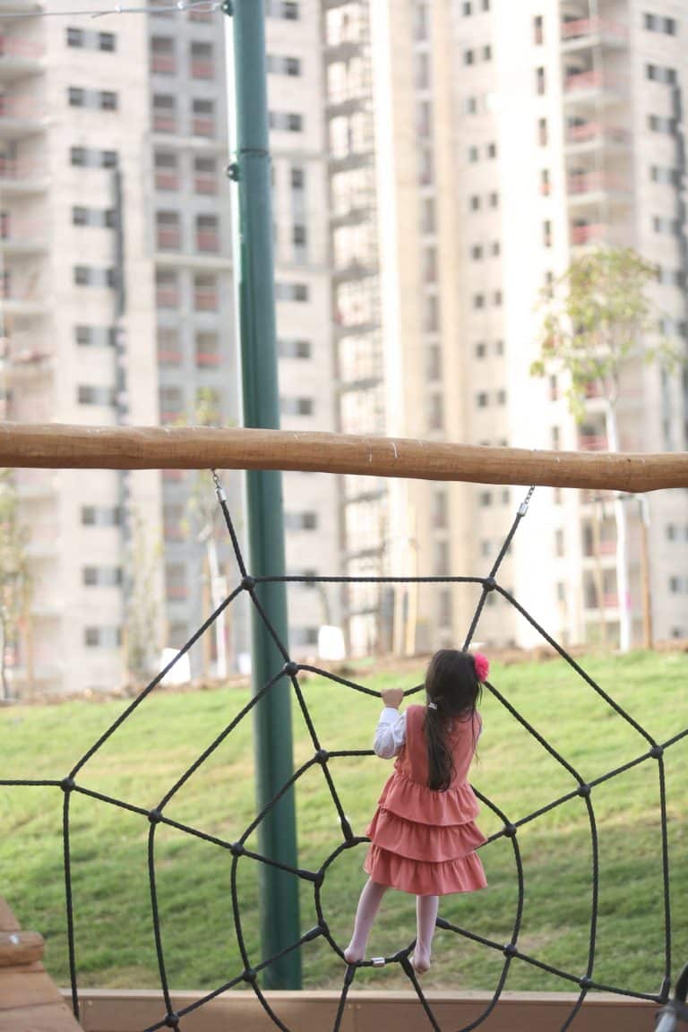 ילדה מטפסת על מתקן דמוי קורי עכביש