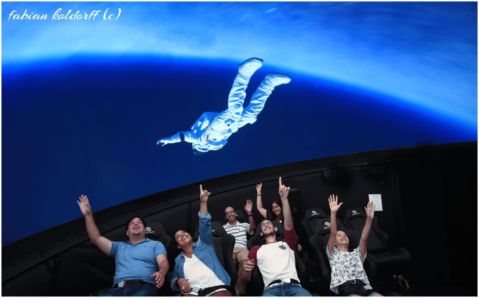 אנשים מצביעים על דמות של אסטרונאוט "מרחף" מעליהם בסרט