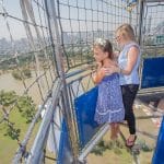 שתי ילדות עומדות על רצפה שקופה בכדור הפורח ומביטות מטה
