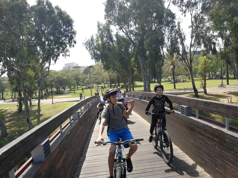 שלושה רוכבי אופניים על גשר עץ בפארק