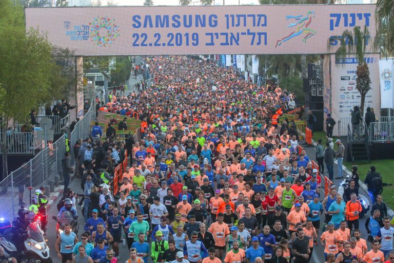 אלפי רצים מתחת לשלט מרתון תל אביב 2019