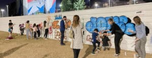 ילדים ומבוגרים מרססים על קיר בסדנת גרפיטי