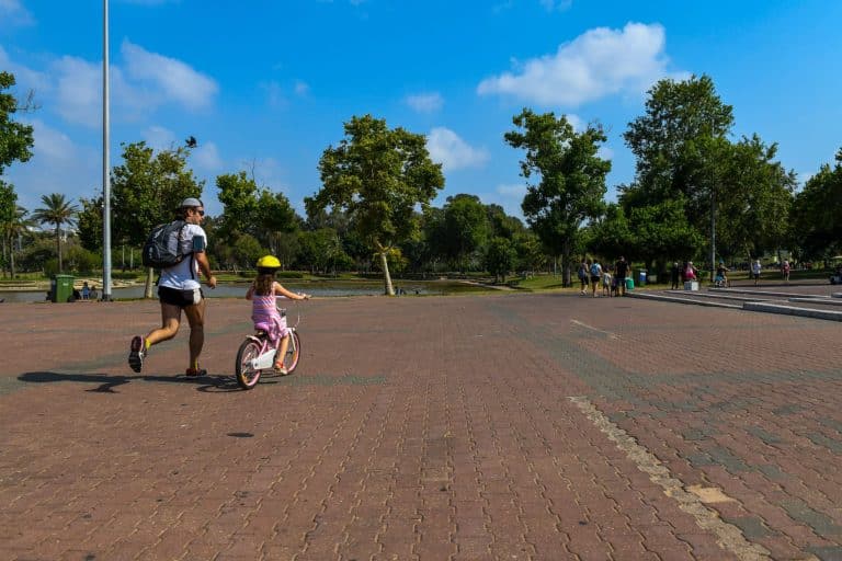 ילדה רוכבת על אופניים ואביה רץ לצידה