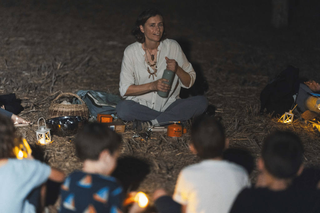 מדריכה יושבת על הארץ ליד גזיה, מכינה תה ומספרת סיפורים