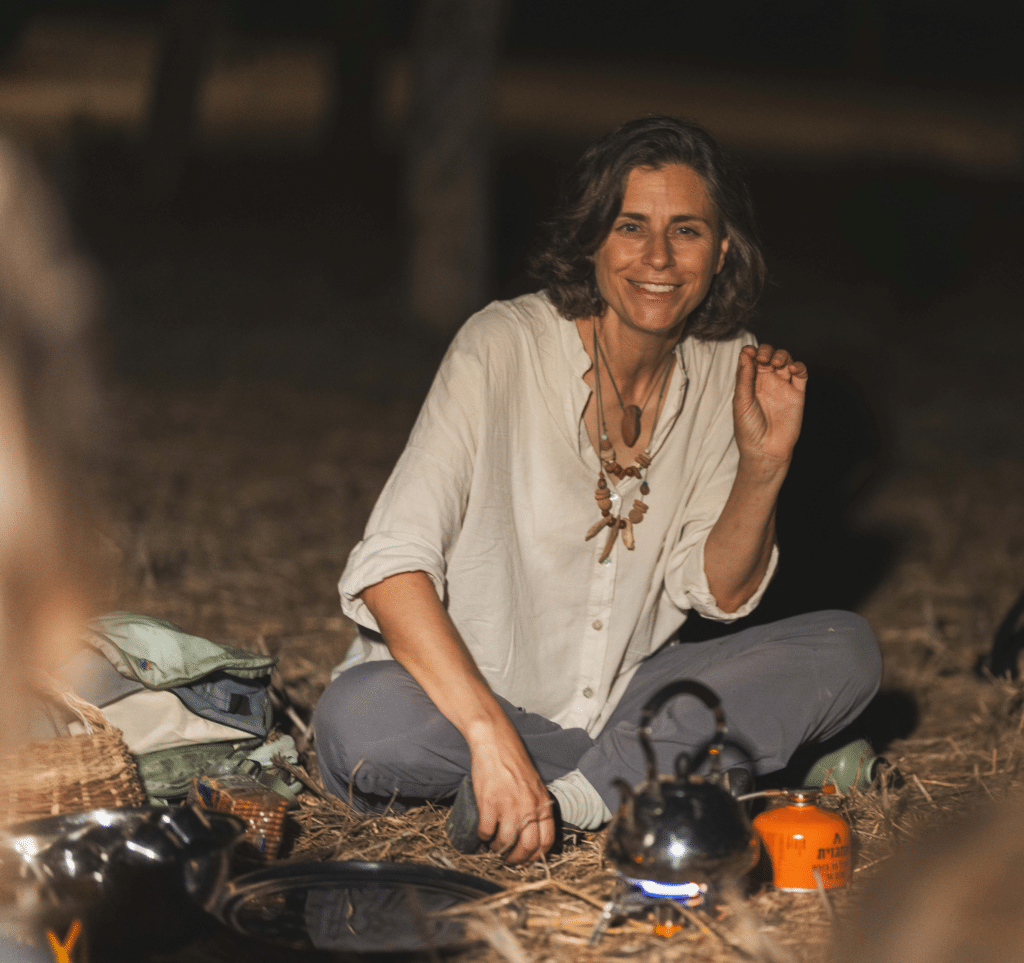 מדריכה יושבת על הארץ ליד גזיה, מכינה תה