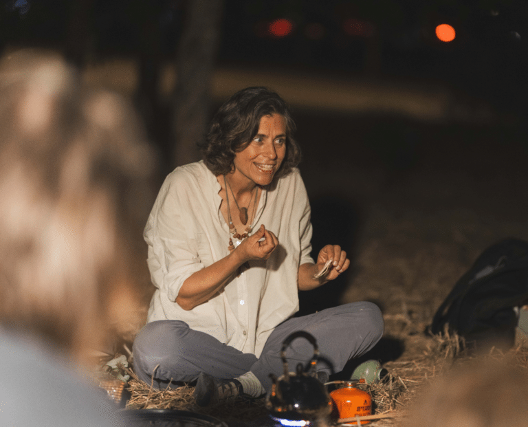 מדריכה יושבת על באדמה ומכינה תה על גזיה