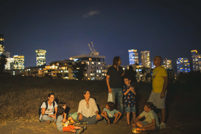 קבוצת ילדים והורים מקשיבים למדריכה בחשיכה
