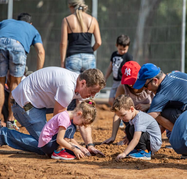 משפחה רוכנת לקרקע לזריעה של פרחי בר