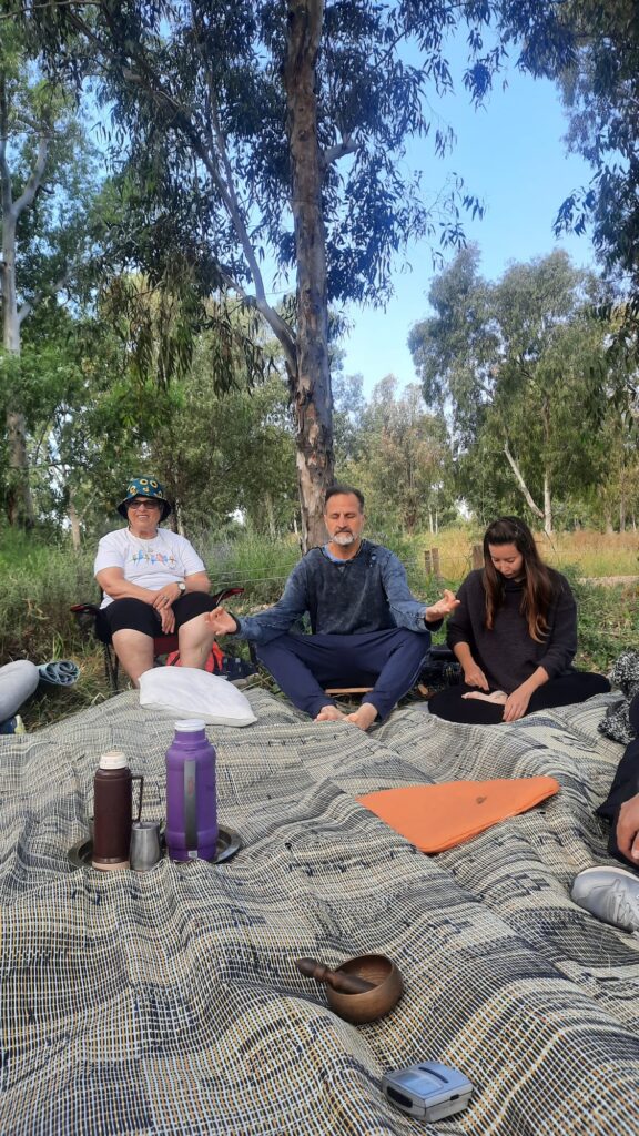 קבוצת אנשים יושבת מתחת לעצים במעגל ריכוז