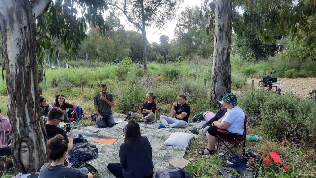 קבוצת אנשים יושבת בחורש במעגל