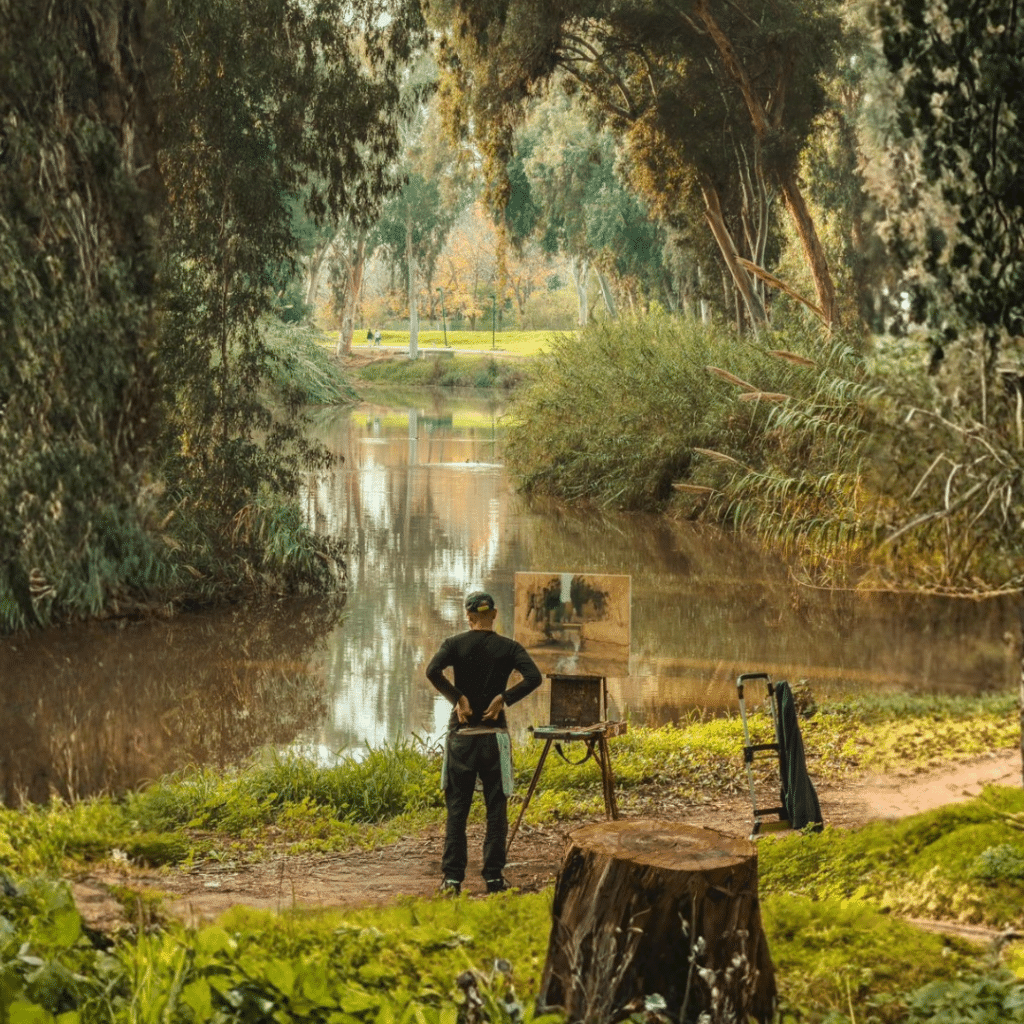 צילום של צייר בעת המנוחה מציור שהוא מצייר על מהשנראה כמו דיקט