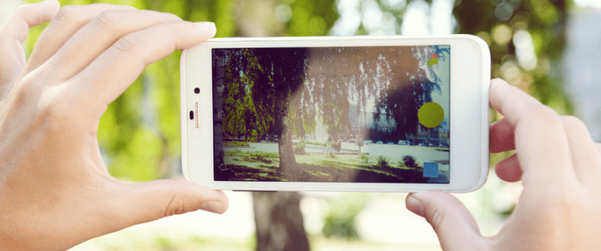 ידיים של ילד מחזיקות סמארטפון ומצלמות עץ