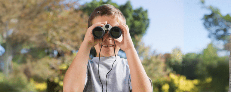 ילד מצמיד משקפת לפניו ומביט למצלמה