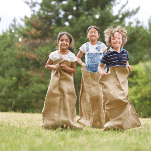 3 ילדים רצים בתוך שקי קמח בפארק
