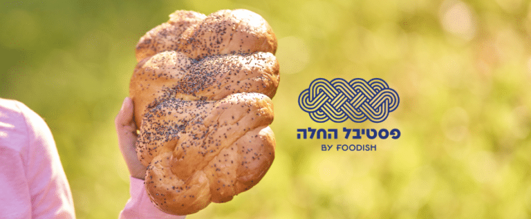 יד אוחזת בחלה אפויה על רקע ירוק