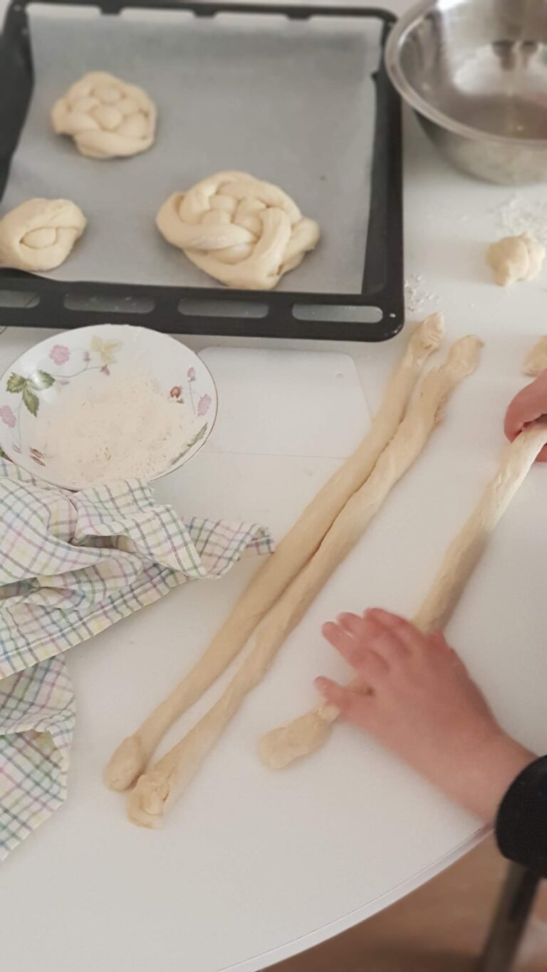 ידיים קולעות צמת חלה על גבי שולחן לבן