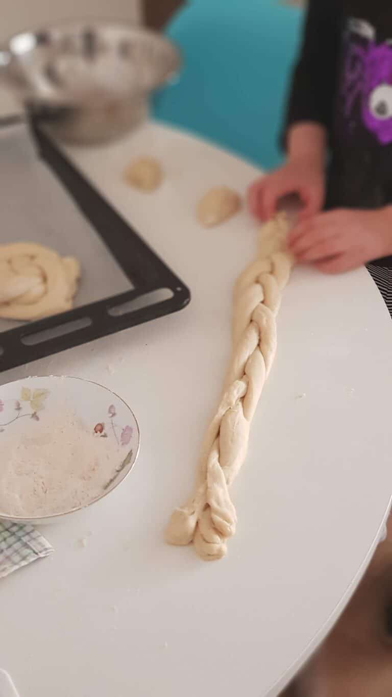 ידיים קולעות צמת חלה על גבי שולחן לבן