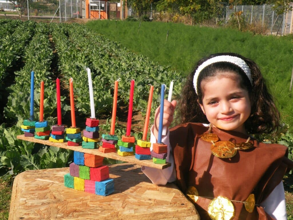 ילדה מתוקה אוחזת נר ולידה חנוכייה צבעונית