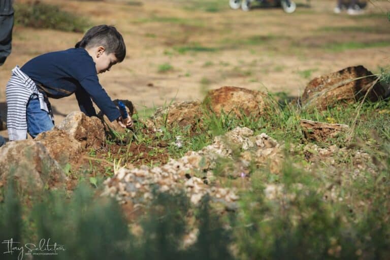 ילד בחולצה שחורה עודר באת