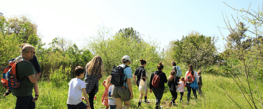 חבורת מטיילים הורים וילדים צועדים בעקבות