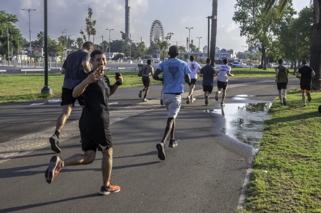 קבוצת אנשים רצה בשביל השרון בפארק. אחד מהם מחייך למצלמה