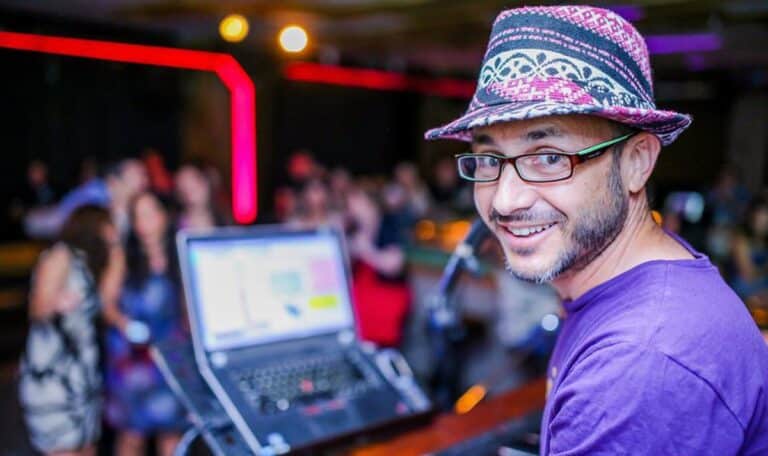 נגן בכובע ומשקפיים מחייך למצלמה וברקע הקהל