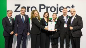 צוות נשים וגברים מחייכים, לבושים חליפות ואוחזים בתעודת הזכיה 