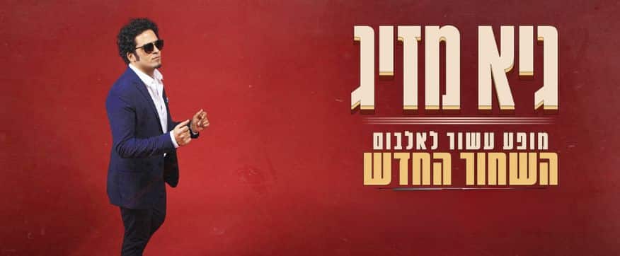 גיא מזיג לבוש חליפה שחורה על רקע אדום