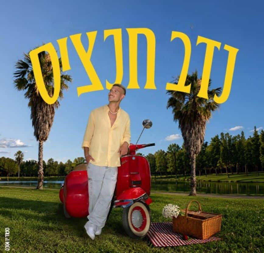 נדב חנציס נשען על וספה אדומה בפארק